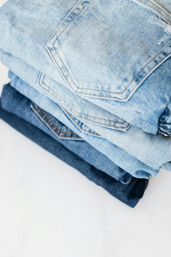 A neatly stacked pile of blue denim jeans showcasing various shades and styles in a minimalist setting.