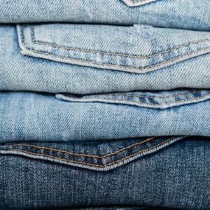 Close-up view of stacked denim jeans showcasing different shades and styles for fashion retail.