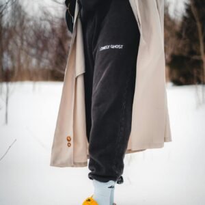 Stylish ensemble featuring a coat and sneakers in a snowy winter setting, highlighting fashion trends.