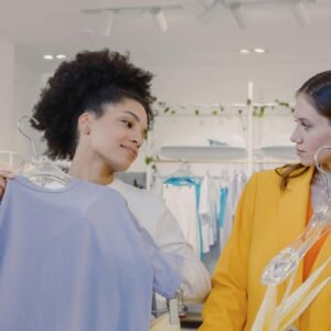 Two women explore fashion choices in a modern boutique, enjoying shopping together.